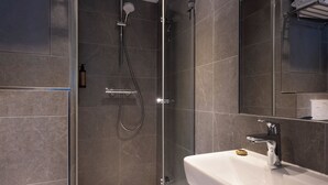 A modern bathroom with a glass-enclosed shower, a white sink, and a mirror above the sink.