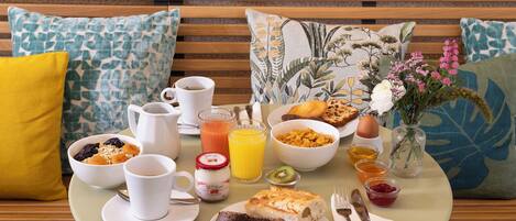 A breakfast setup on a round table with a variety of food items, including cereal, toast, and fruit, along with coffee and juice.