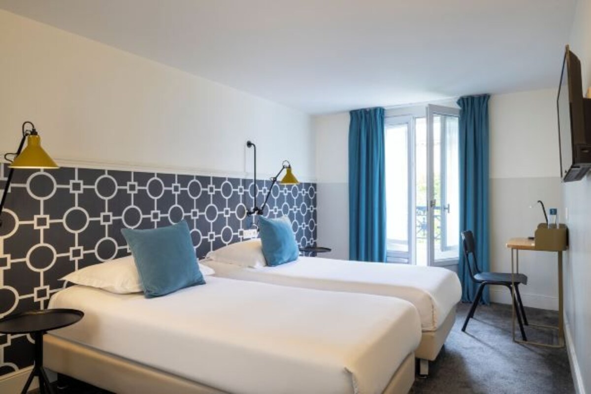 Una camera d'albergo con due letti, una scrivania e una sedia.