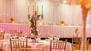 A banquet hall with round tables set for a formal event, featuring candelabras and floral centerpieces.