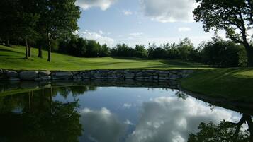 A serene golf course with a pond reflecting trees and sky.