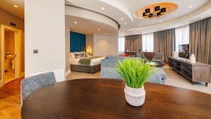 A modern living room with a curved ceiling, a dining table with a potted plant, and a cozy seating area with a sofa and armchairs. - Mount Wolseley Hotel, Golf and Spa Resort (Tullow)