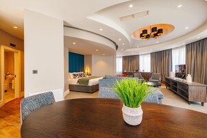 Una sala de estar moderna con techo curvo, una mesa de comedor con planta en maceta y una zona de estar acogedora con sofá y sillones.