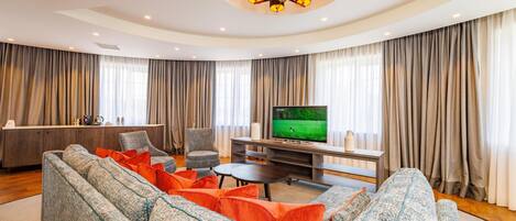 A modern living room with a large sectional sofa, a television, and a dining area.