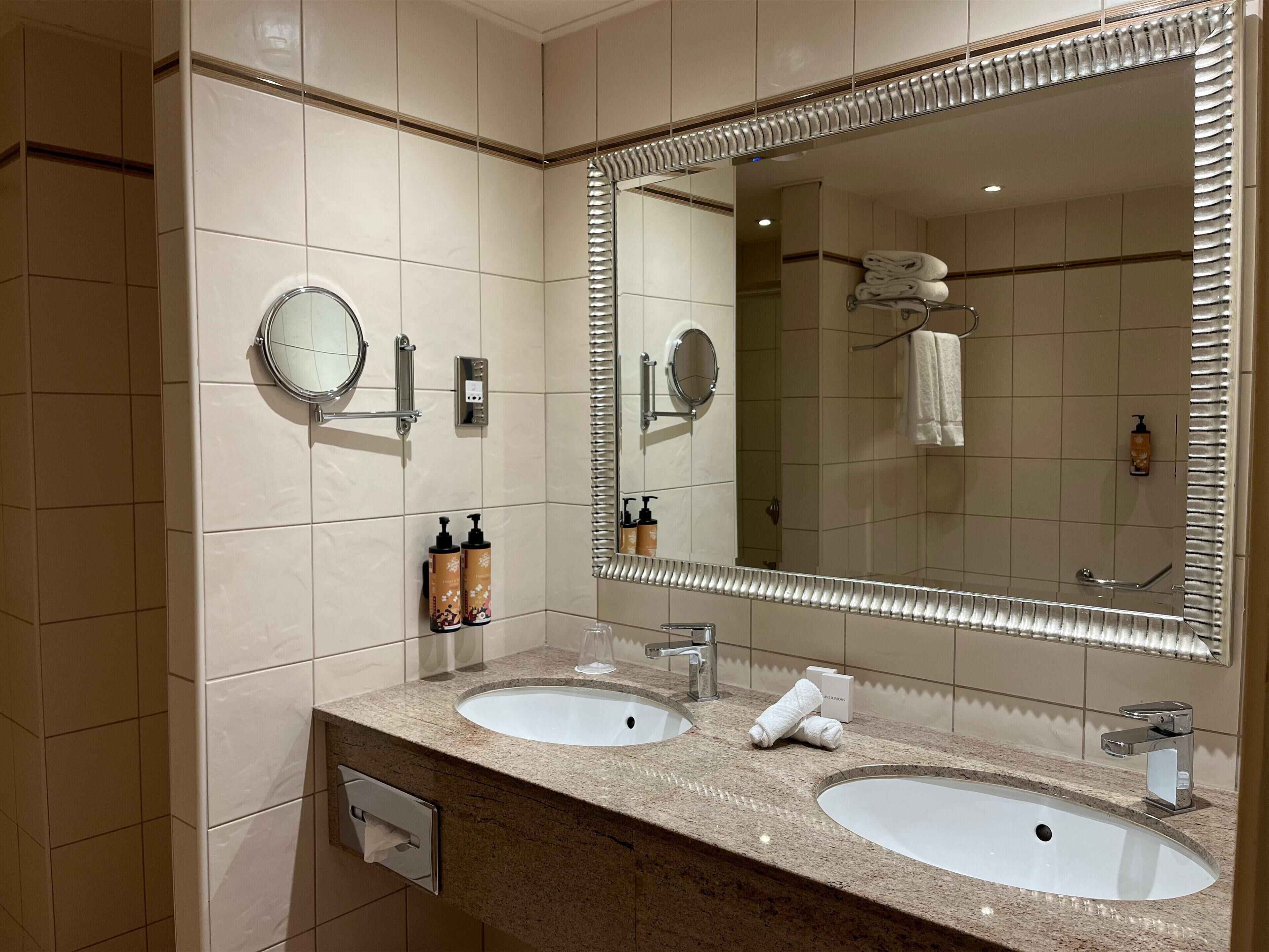 A bathroom with two sinks, a large mirror, and a towel rack.