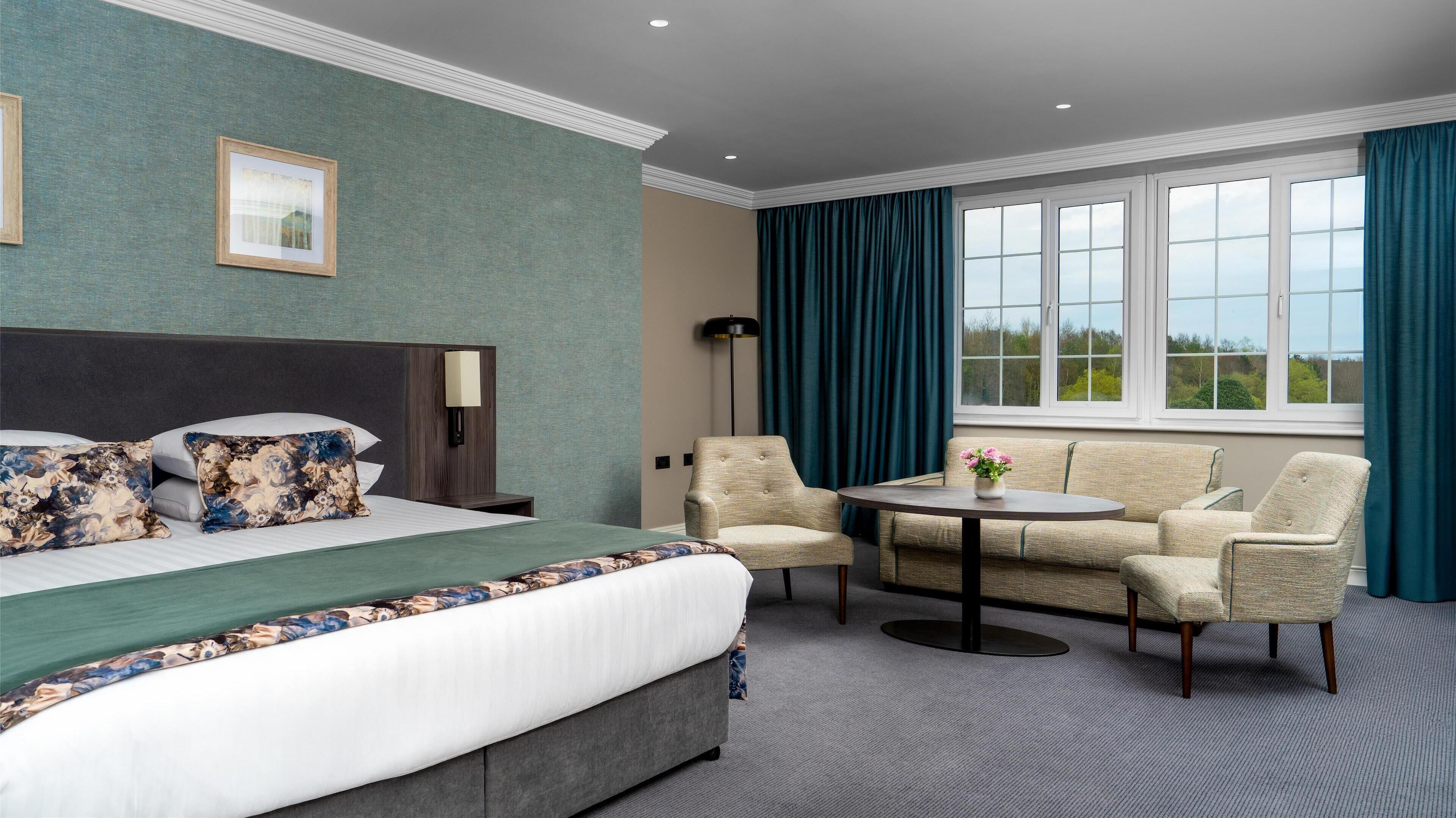Una habitación de hotel con cama, sofá, una mesita y una lámpara de pie.