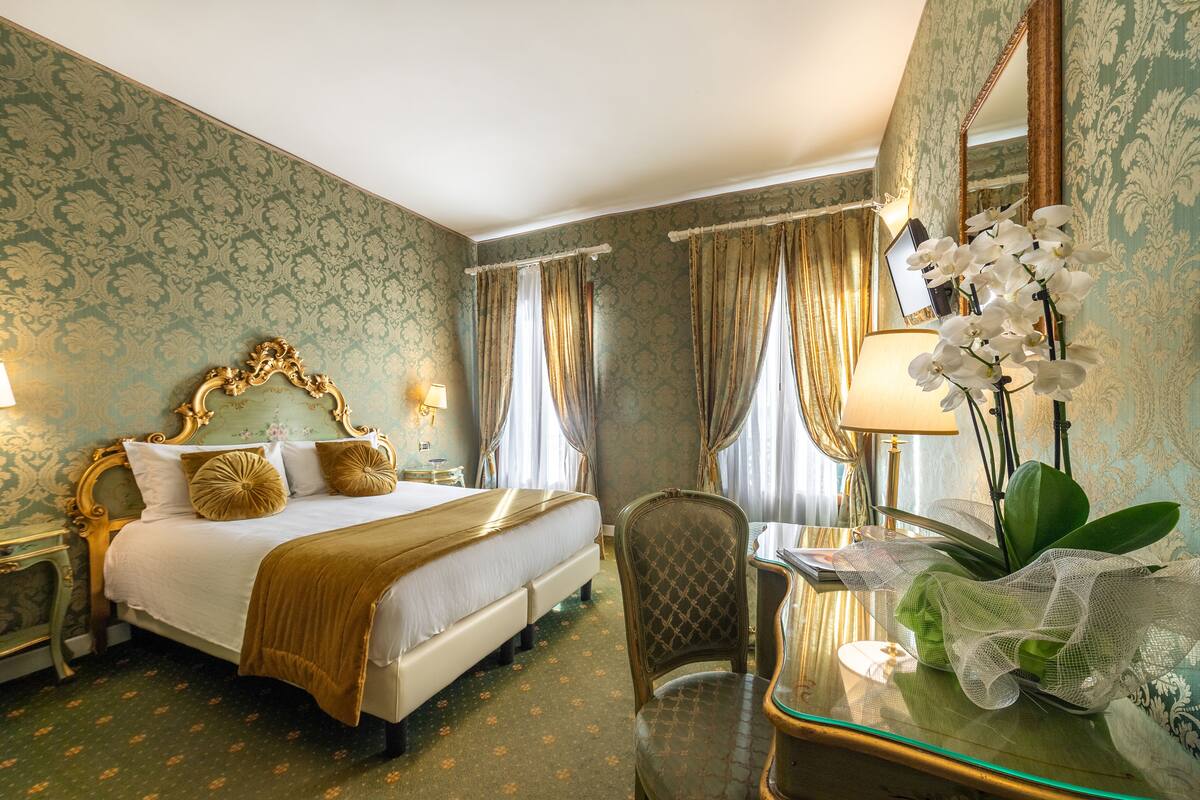 Ein Hotelzimmer mit Bett, Schreibtisch, Stuhl, Lampe und Spiegel.