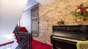 Ein Flügel, eine Treppe mit rotem Teppich und eine Backsteinwand.