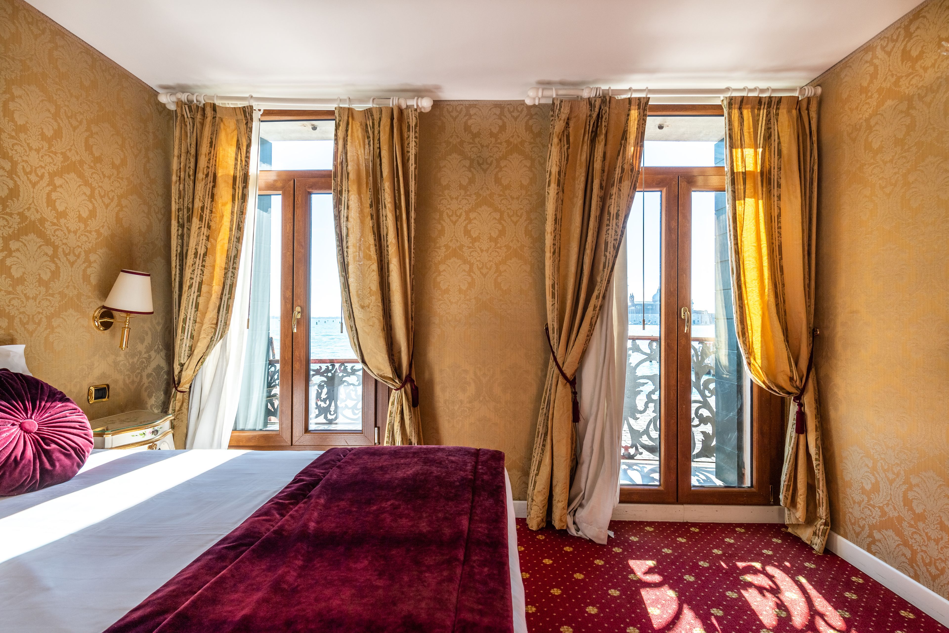 Een hotelkamer met een bed, gordijnen, een raam met uitzicht en een kamerbreed tapijt.