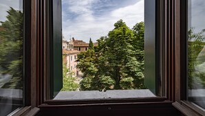 Ein Fenster mit Blick auf ein Gebäude mit einer Kuppel und Bäume im Vordergrund.