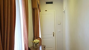 A hallway with wooden flooring, a dining table with chairs, and a door with a number plate. - Hotel Locanda Canal (Venice)