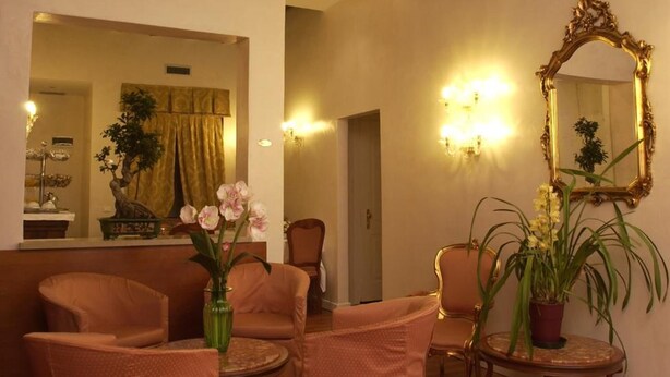 A cozy living room with wooden flooring, a sofa, armchairs, a round coffee table, and a mirror with a gold frame. - Hotel Locanda Canal (Venice)