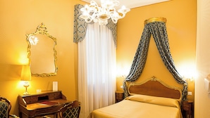 A hotel room with a bed, a desk, a chair, a mirror, and a chandelier. - Hotel Locanda Canal (Venice)