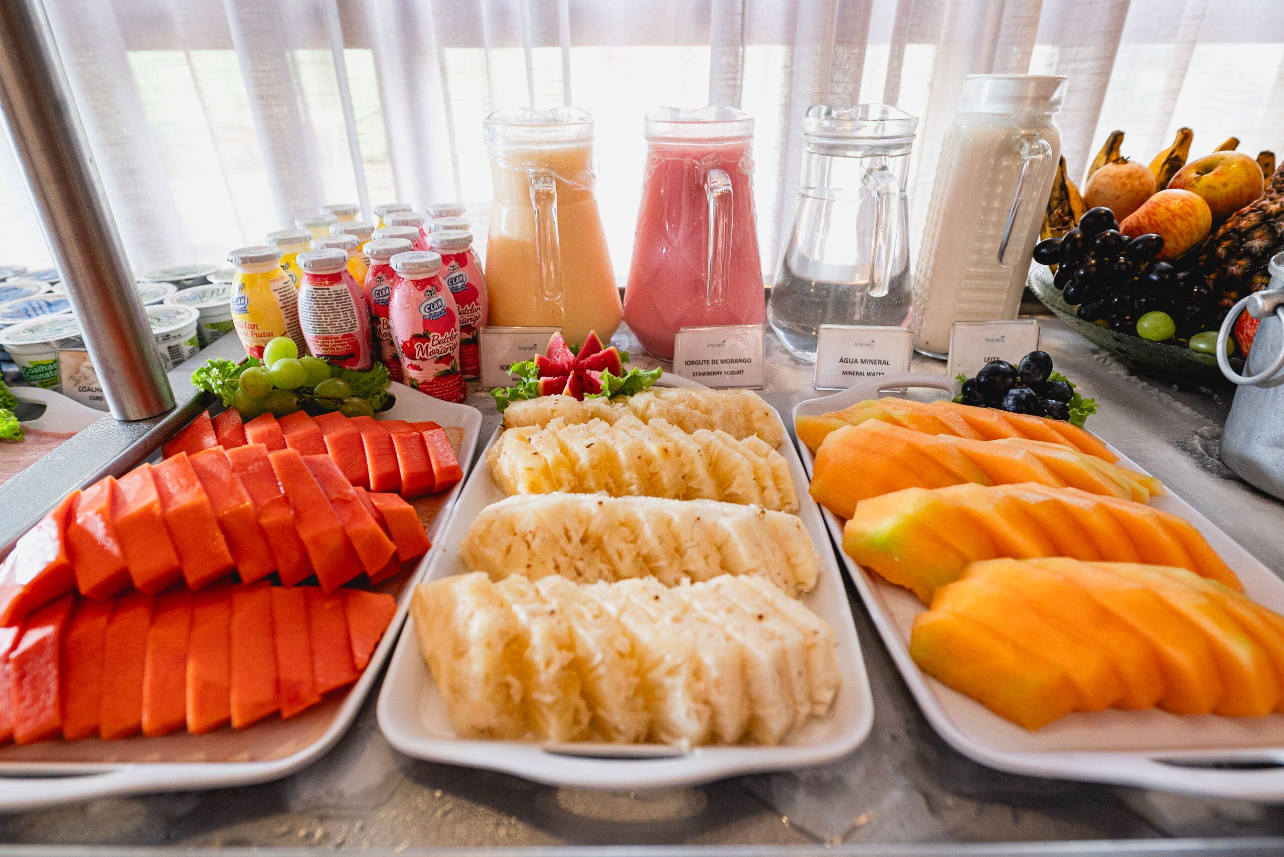 A buffet with various fruits, vegetables, and beverages.