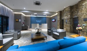 A modern lobby with a reception desk, seating area, and a large screen displaying 'QUALITY SUITES'. - Quality Hotel And Suites Natal (Natal)