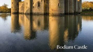 Bodiam Castle, med sina stenmurar och torn, speglas i vattnet.
