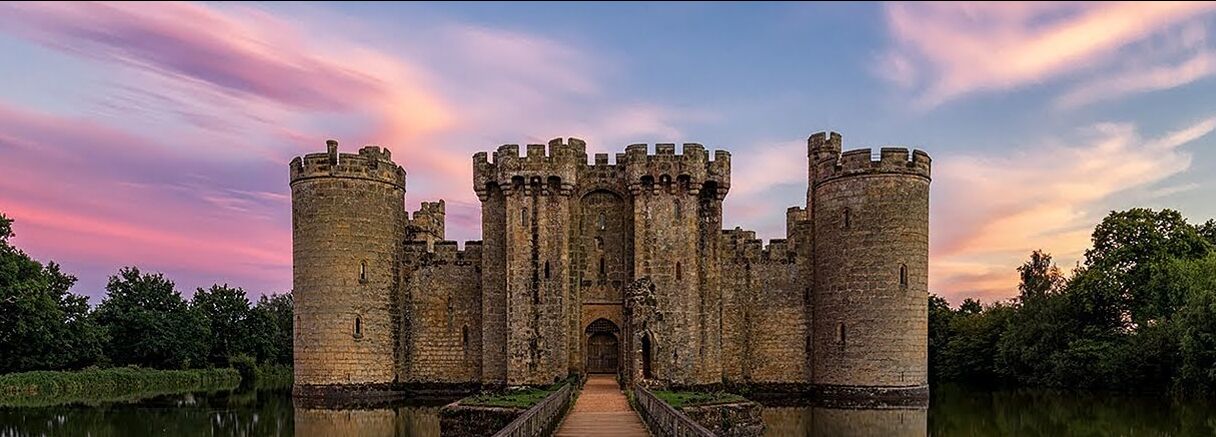 A historic castle with a central courtyard, surrounded by water and greenery.