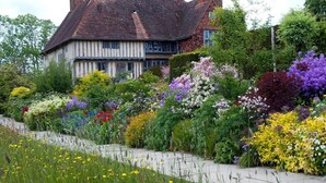 A traditional half-timbered house with a garden full of colorful flowers and a stone pathway. - London Beach Country Hotel (Tenterden)