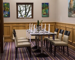 Comedor con una mesa dispuesta para seis comensales, seis sillas y un ventanal con vista a árboles.
