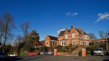 A large brick building with a prominent entrance and a staircase leading up to the main doors.