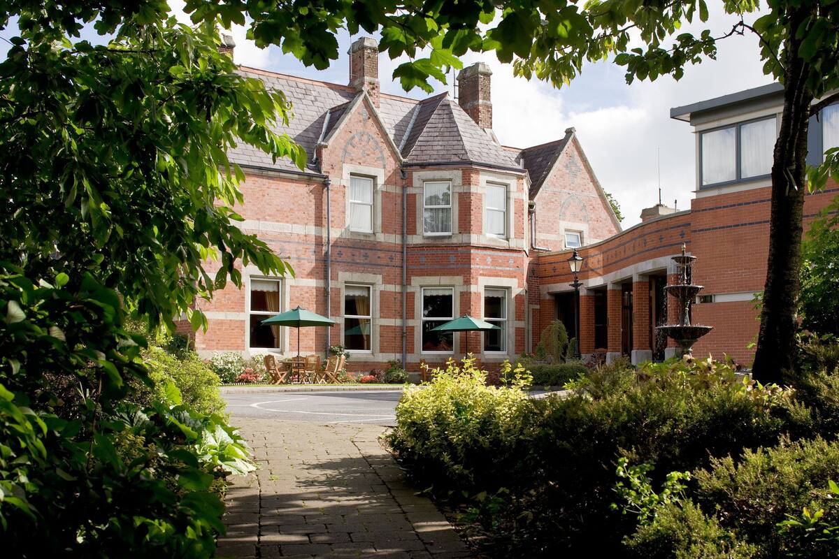 A brick building with a garden patio, outdoor seating, and a fountain.
