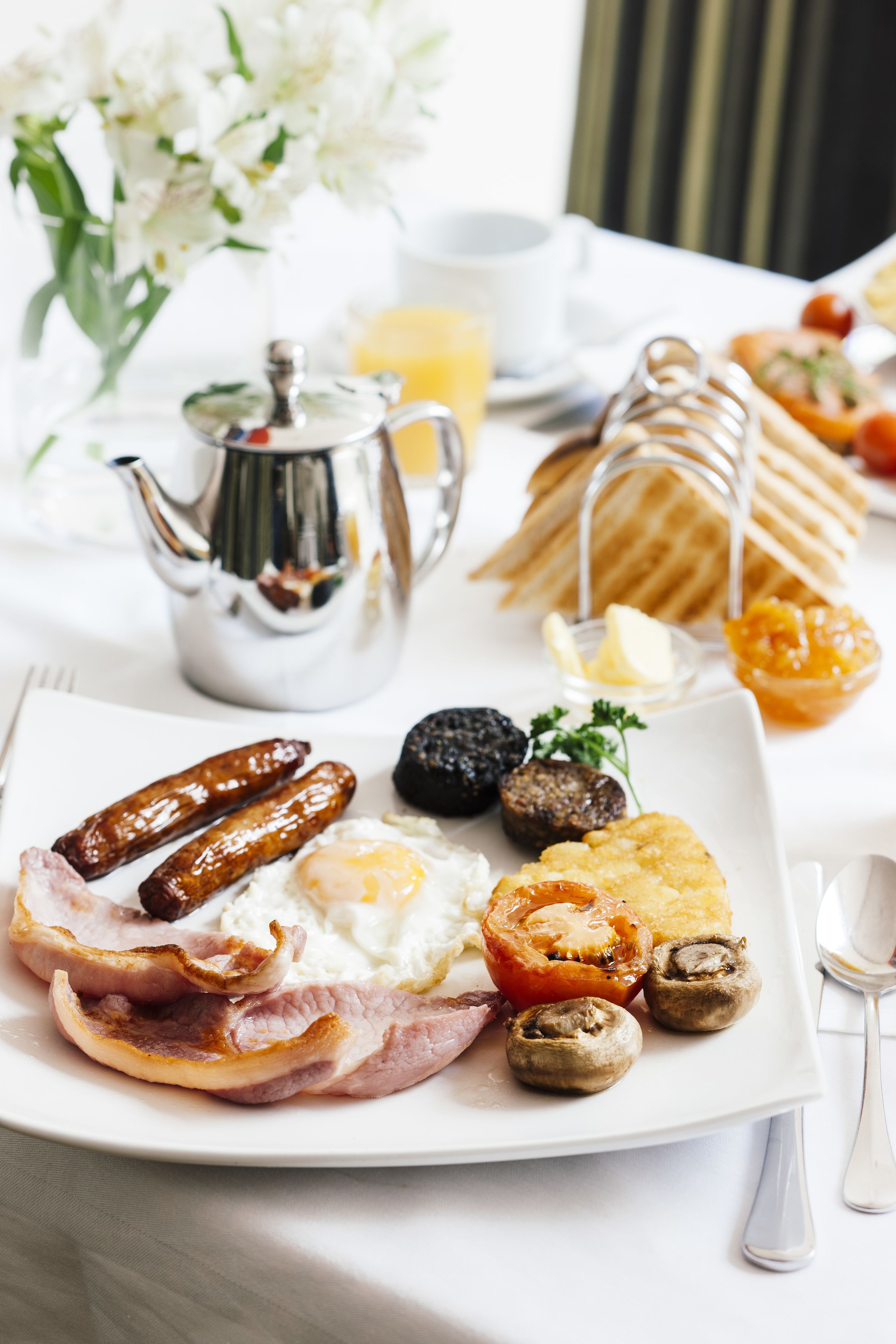 Une assiette de petit-déjeuner comprenant des saucisses, des œufs, des champignons et du bacon.