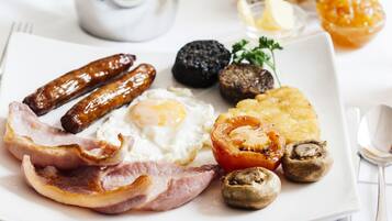 Une assiette de petit-déjeuner comprenant des saucisses, des œufs, des champignons et du bacon.