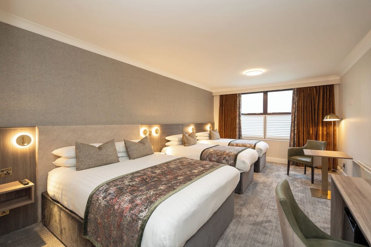 A hotel room with two beds, a desk, and a chair.
