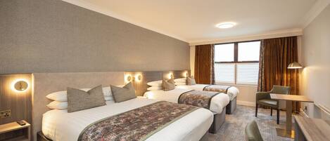 A hotel room with two beds, a desk, and a chair.