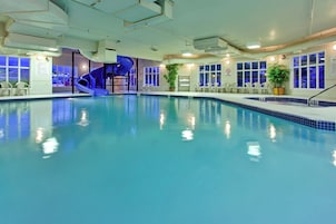 An indoor swimming pool with a blue slide, seating area, and a no diving sign.