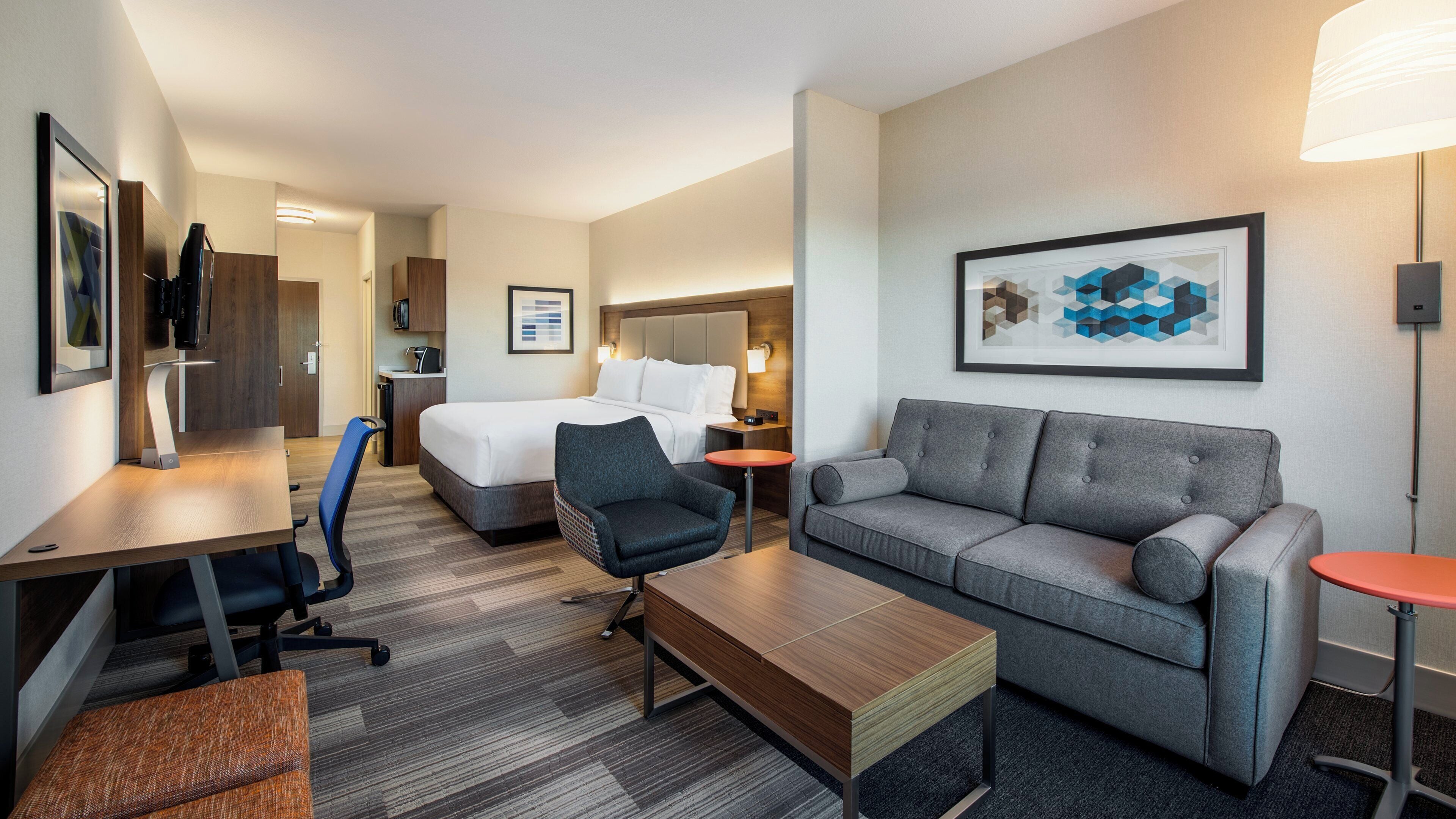 A hotel room with a bed, a sofa, a desk, and a chair.