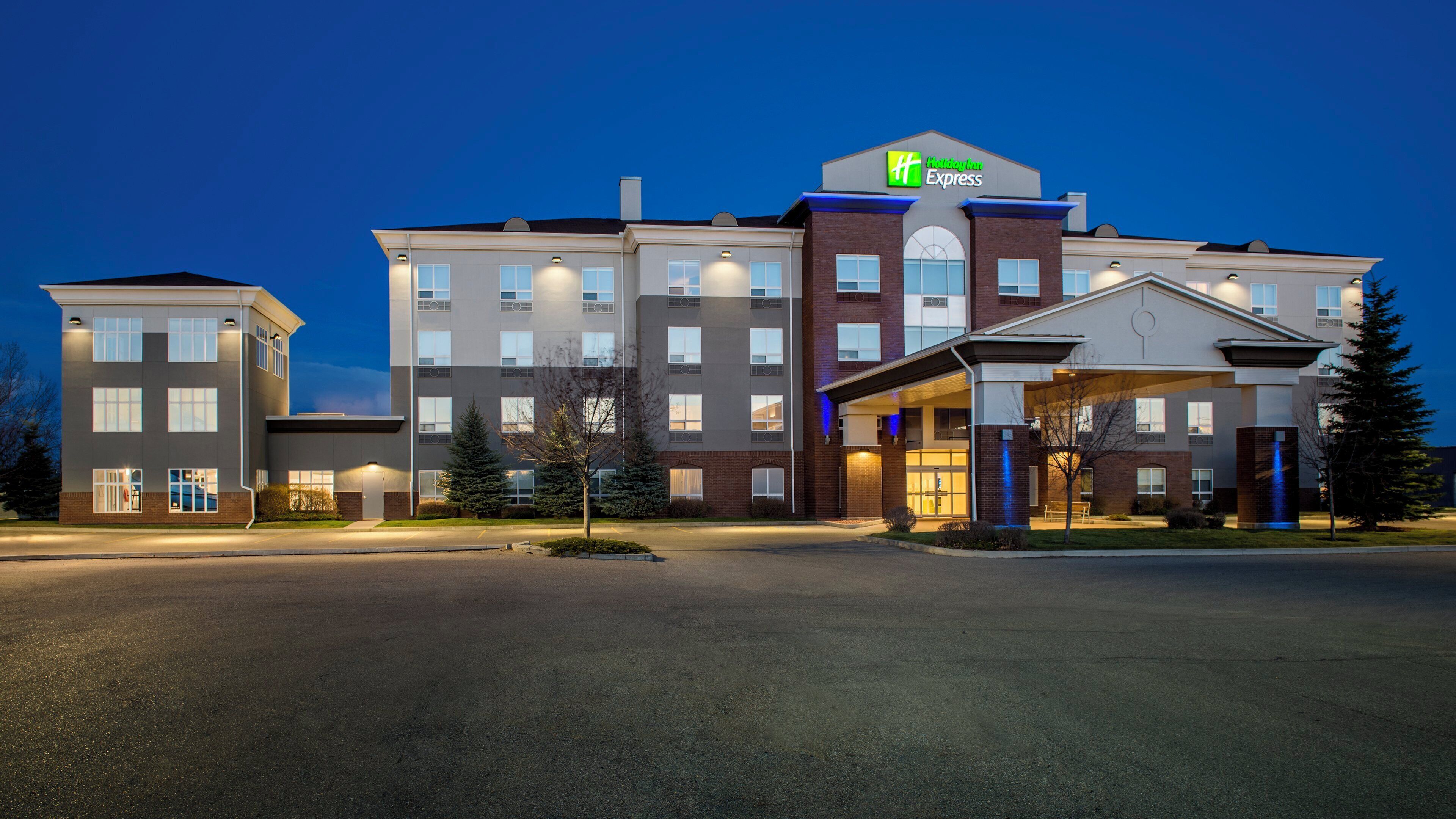 A multi-story hotel with a prominent Holiday Inn Express sign, a covered entrance, and a parking lot.