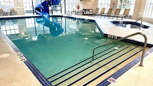 An indoor swimming pool with a blue slide, clear water, and a no diving sign.