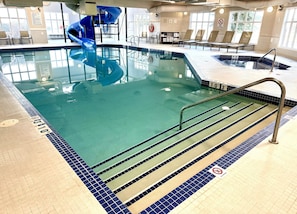 An indoor swimming pool with a blue slide, clear water, and a no diving sign. - Holiday Inn Express Hotel & Suites Airdrie-Calgary North by IHG (Airdrie)