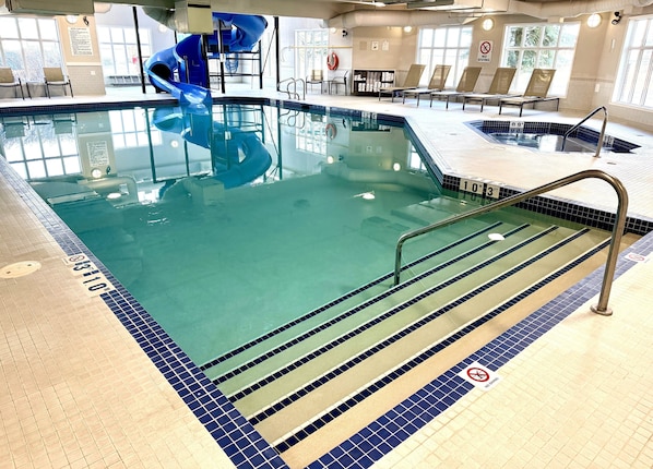 An indoor swimming pool with a blue slide, clear water, and a no diving sign. - Holiday Inn Express Hotel & Suites Airdrie-Calgary North by IHG (Airdrie)