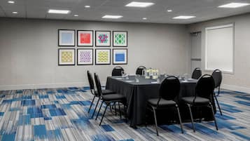 A conference room with a round table, black chairs, and a carpeted floor.