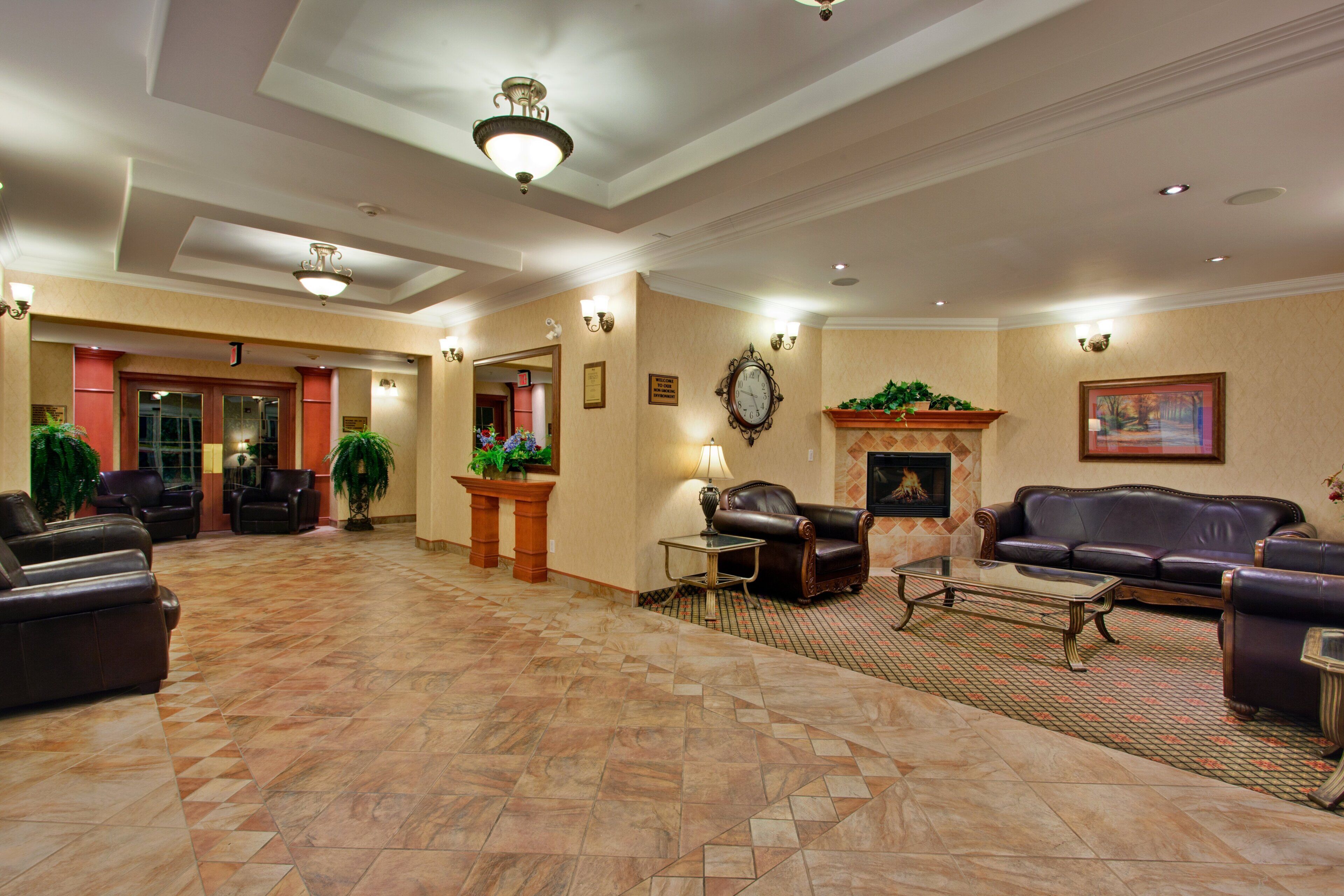 A spacious lobby with a fireplace, leather seating, and a patterned floor.