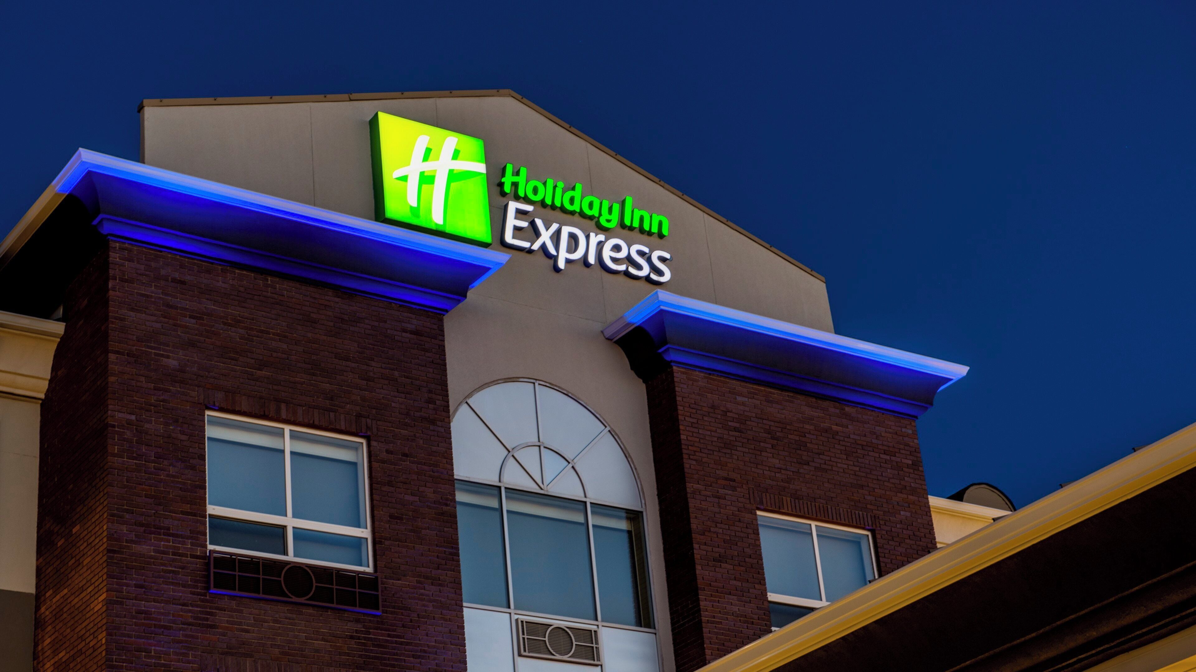 Edificio de Holiday Inn Express con un letrero llamativo, ventanas grandes y fachada de ladrillo.