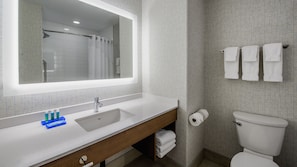 Een moderne badkamer met een grote spiegel, een wastafel, een toilet en een douchehoek.