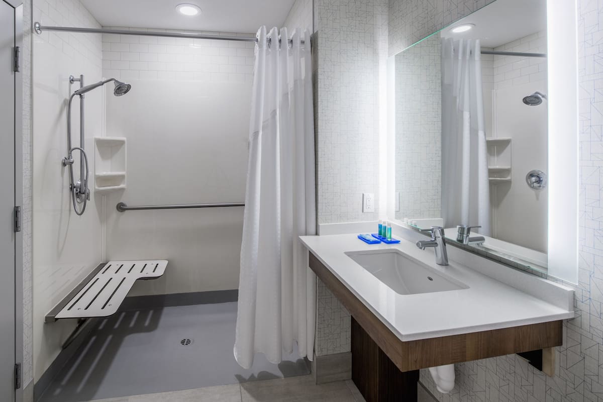 A modern bathroom with a shower, a sink, and a mirror.
