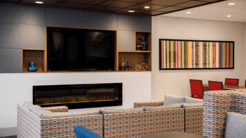 Una sala de estar moderna con un televisor de pantalla plana, chimenea y un cuadro abstracto colorido.