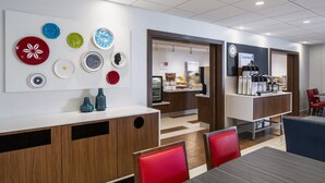A modern cafe with a variety of colorful plates on display, a coffee machine, and seating areas.