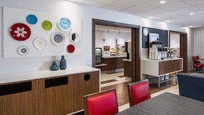 Een modern café met diverse kleurrijke borden, een koffiemachine en zithoeken.