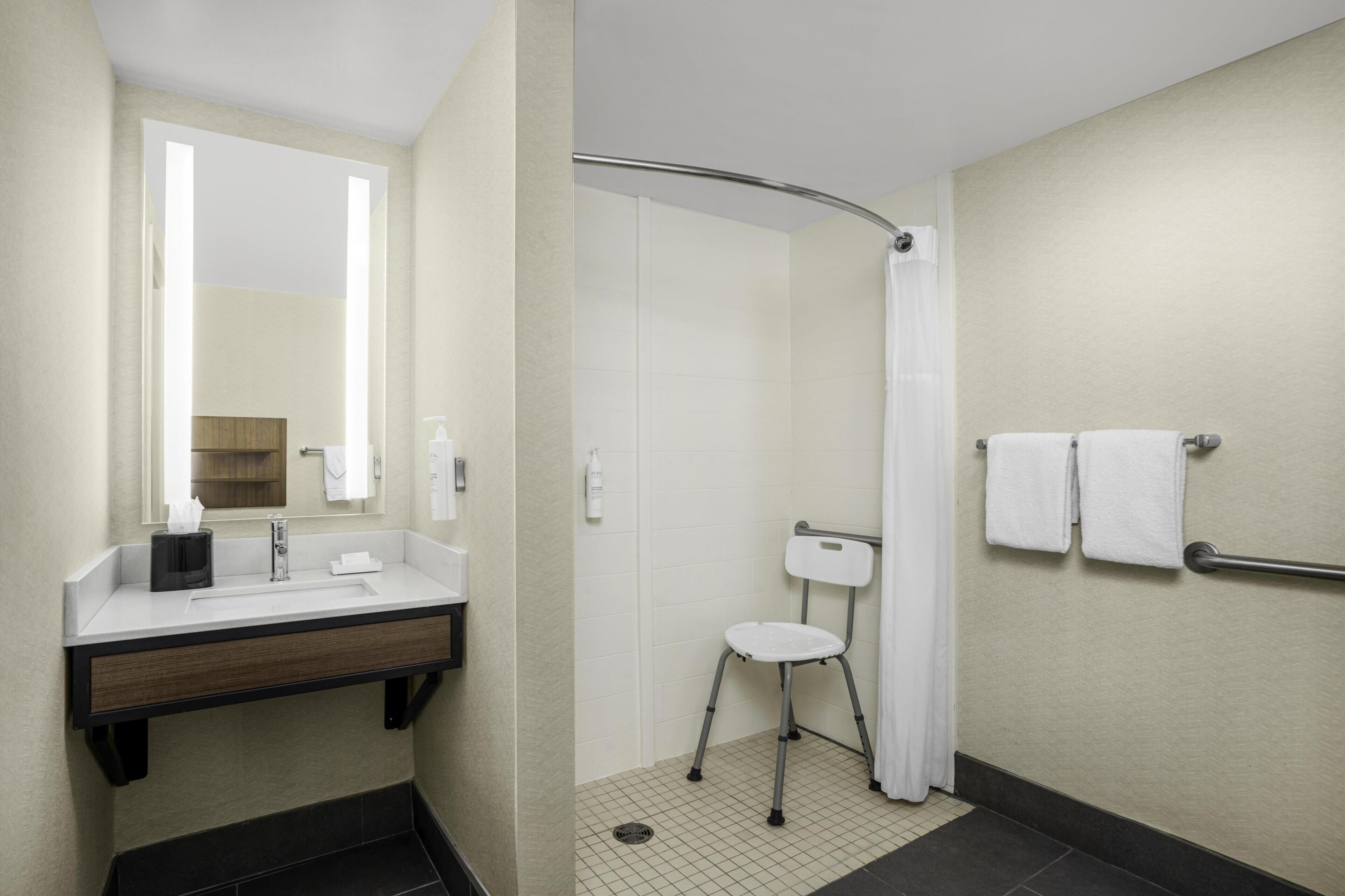 A bathroom with a sink, mirror, and shower.