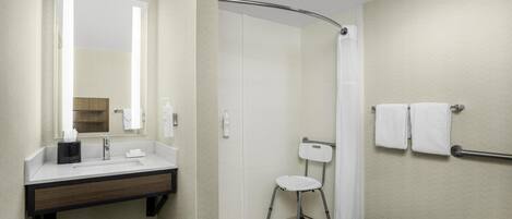 A bathroom with a sink, mirror, and shower.