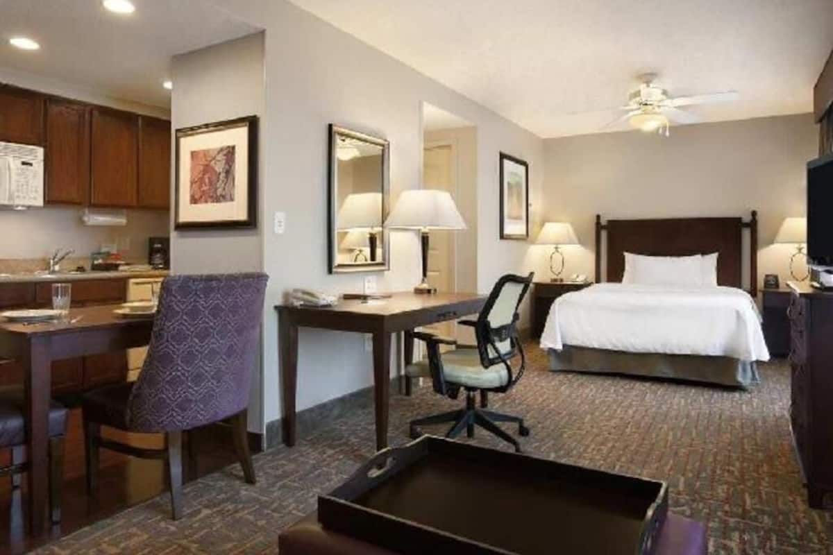 A hotel room with a bed, desk, chair, and a small dining table.
