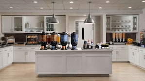 Una cocina moderna con una isla central, cafeteras y una variedad de electrodomésticos.