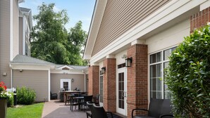 Un patio con mobiliario exterior y una parrilla.