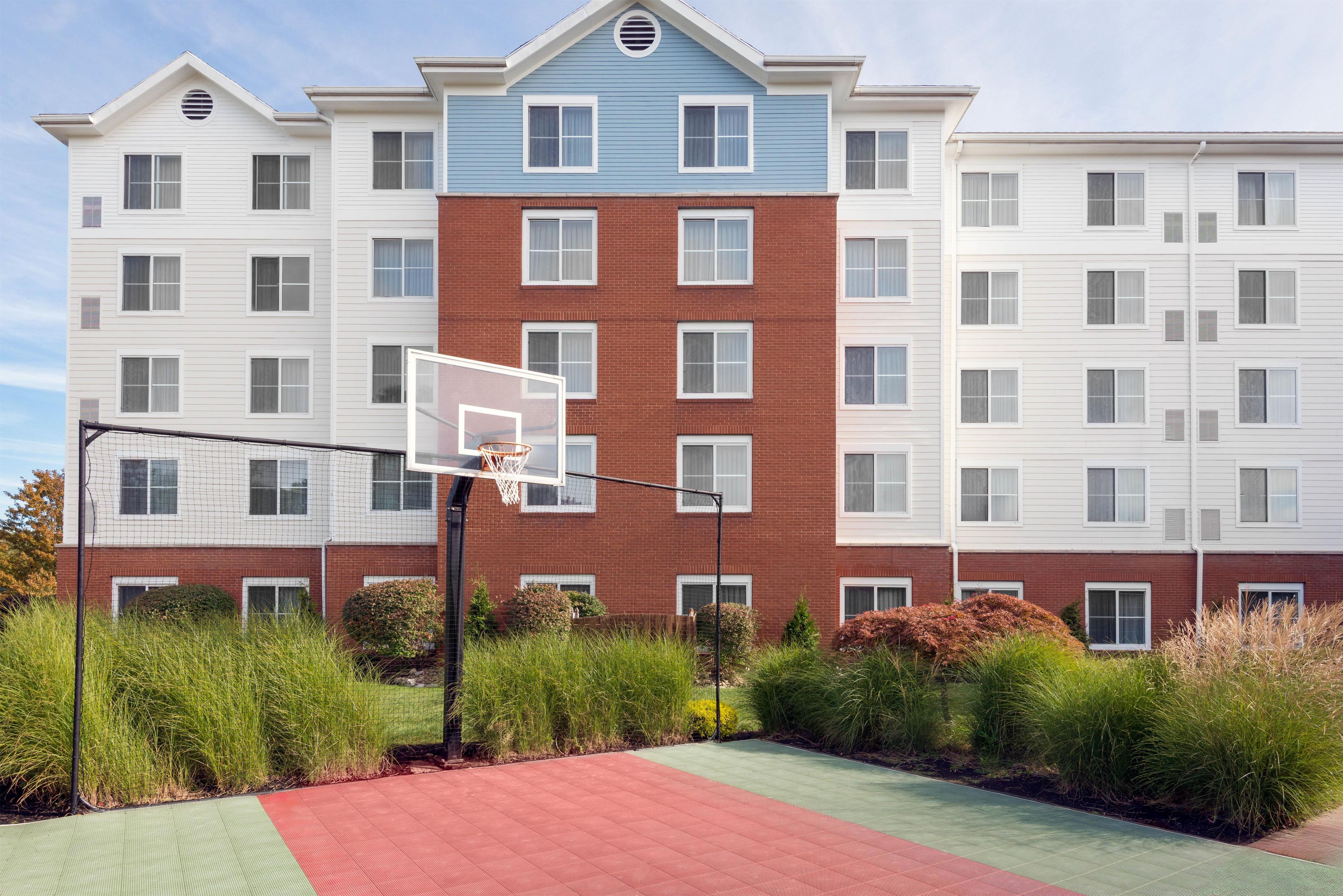 A residential building with a basketball court in front.