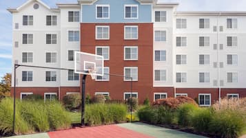 A residential building with a basketball court in front.